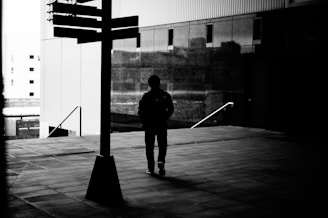 man in black jacket and pants walking on sidewalk during daytime