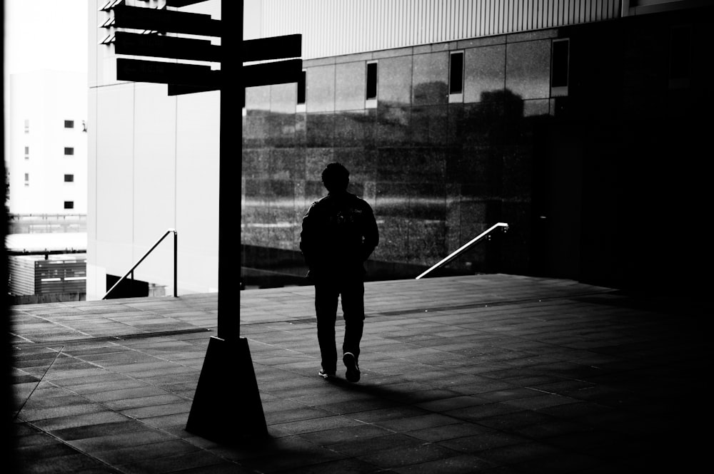 man in black jacket and pants walking on sidewalk during daytime