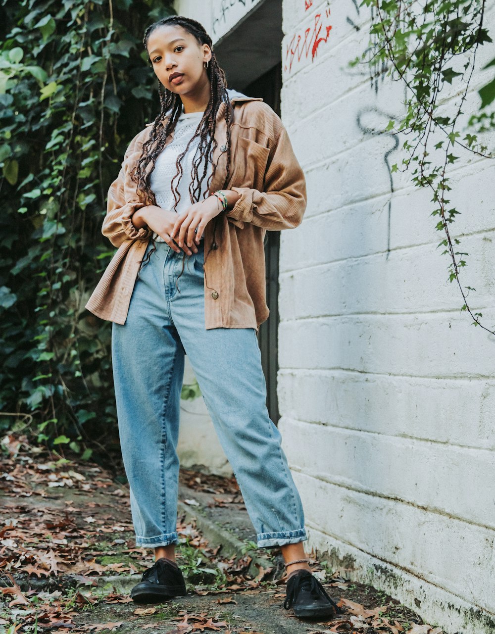 a woman standing in front of a white brick wall