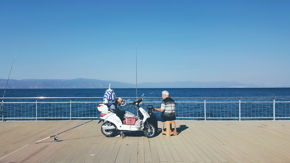 a man and a woman standing next to a scooter