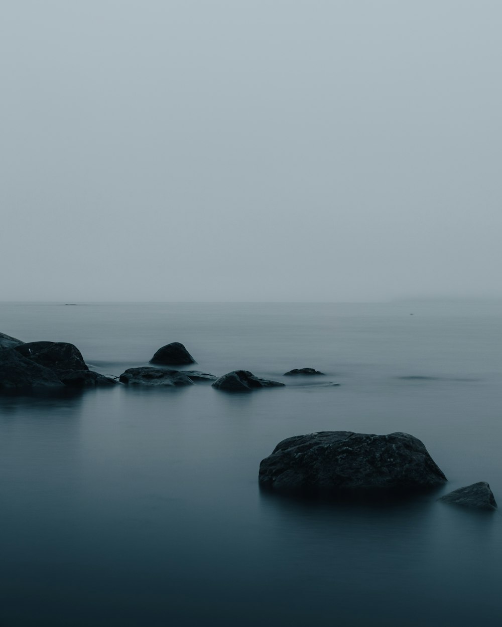 uma foto em preto e branco de rochas na água
