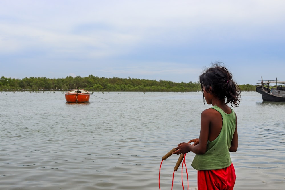 a little girl standing in the water with a dog