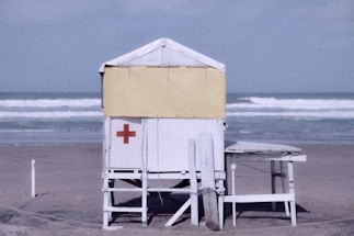 a lifeguard chair on the beach with a lifeguard tower in the background