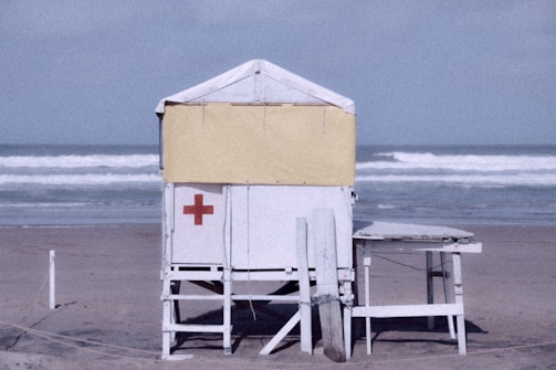 a lifeguard chair on the beach with a lifeguard tower in the background