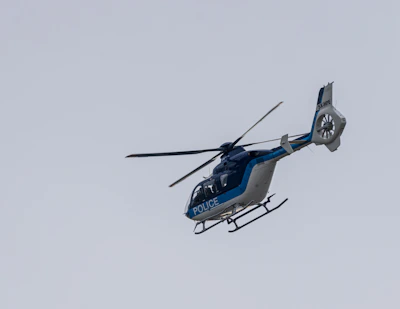 A police helicopter flying over a city during a manhunt operation