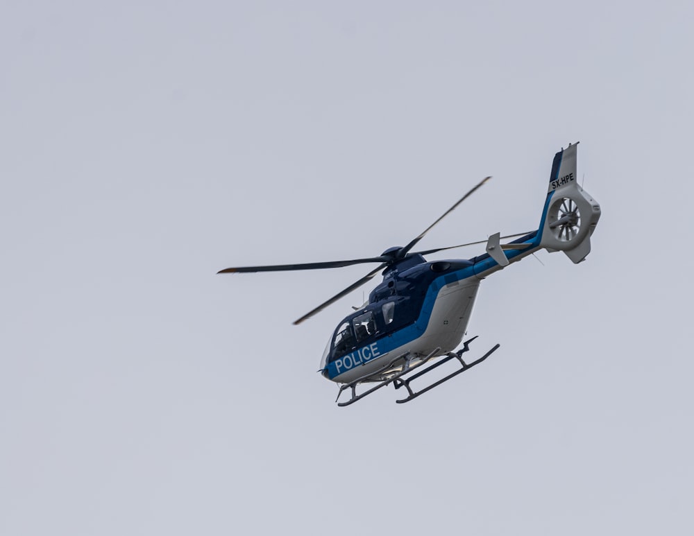 a blue and white helicopter flying in the sky
