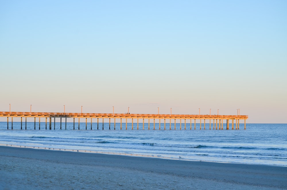 a long wooden pier sitting on top of a beach next to the ocean