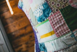 A beautifully finished signature quilt laid out on a wooden table with handwritten guest messages visible on fabric squares.