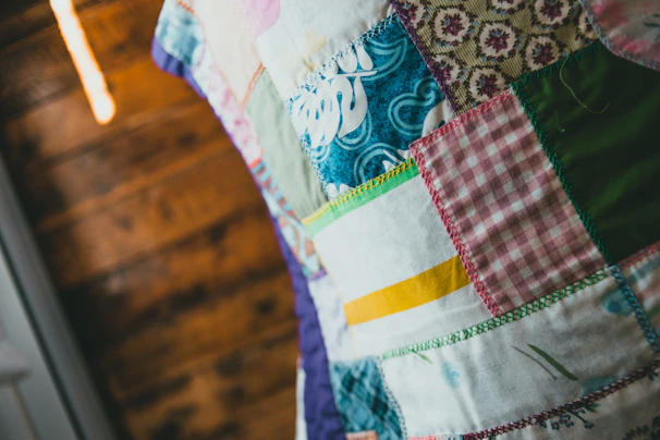 Close-up of hands quilting a colorful patchwork, showcasing community creativity and heritage