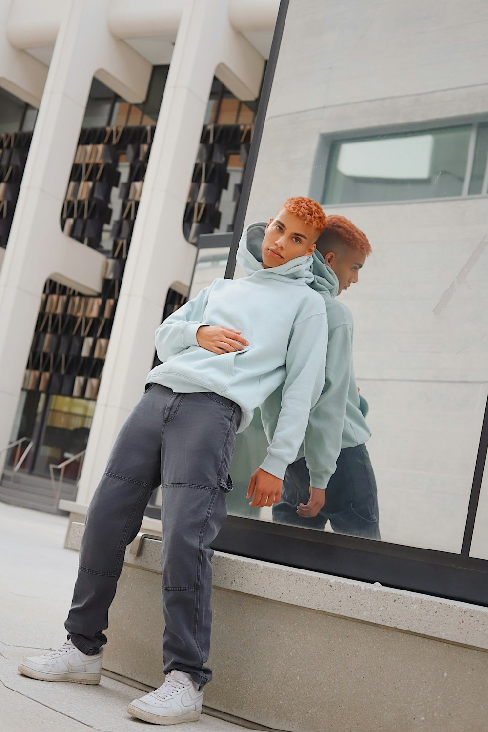 woman in teal hoodie and blue denim jeans sitting on white bench