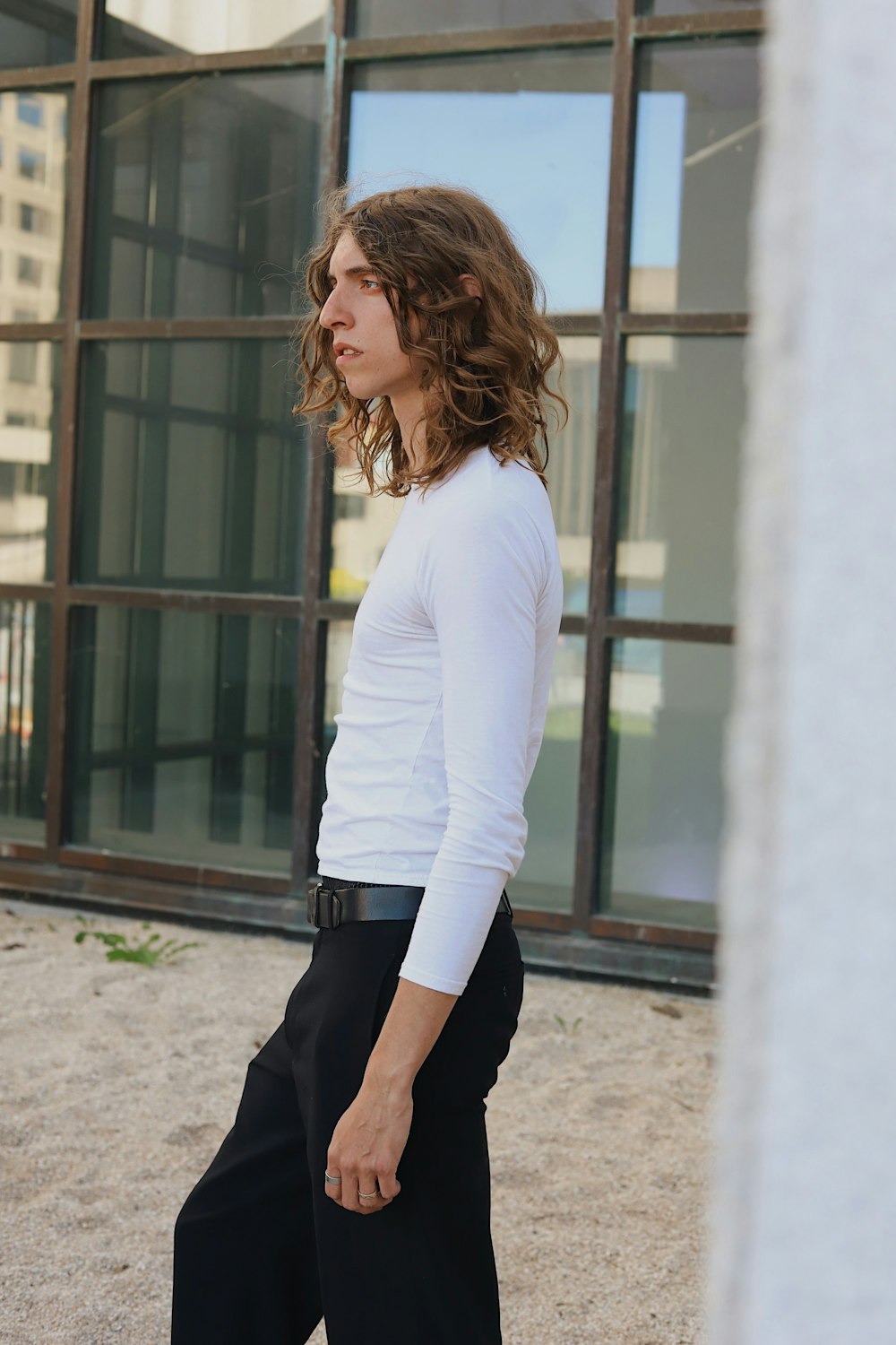 woman in white long sleeve shirt and black pants standing near window during daytime