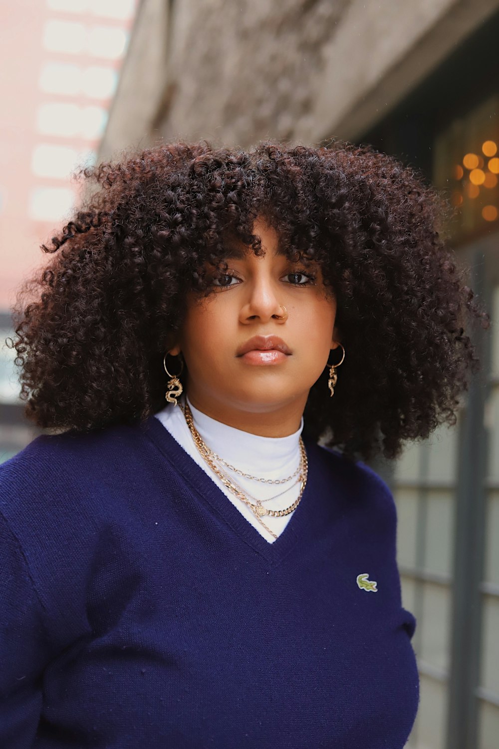 a woman wearing a blue sweater and gold earrings