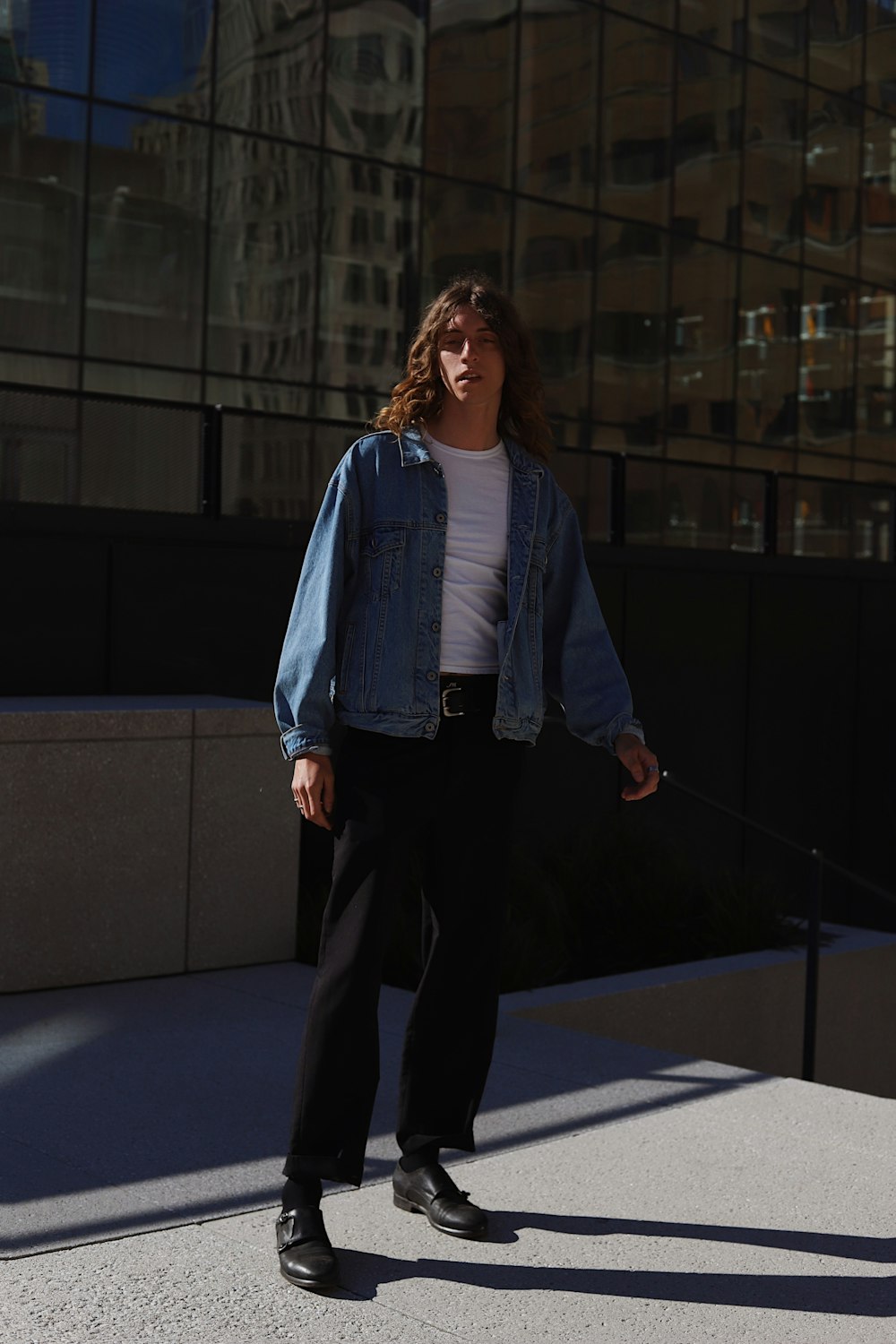 woman in blue denim jacket and black pants standing on blue floor