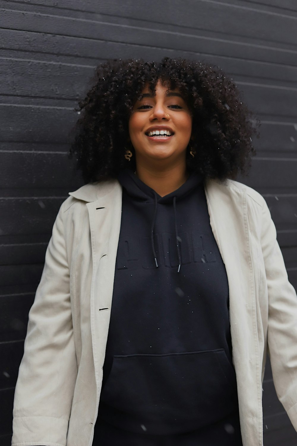 woman in white coat standing near gray wall