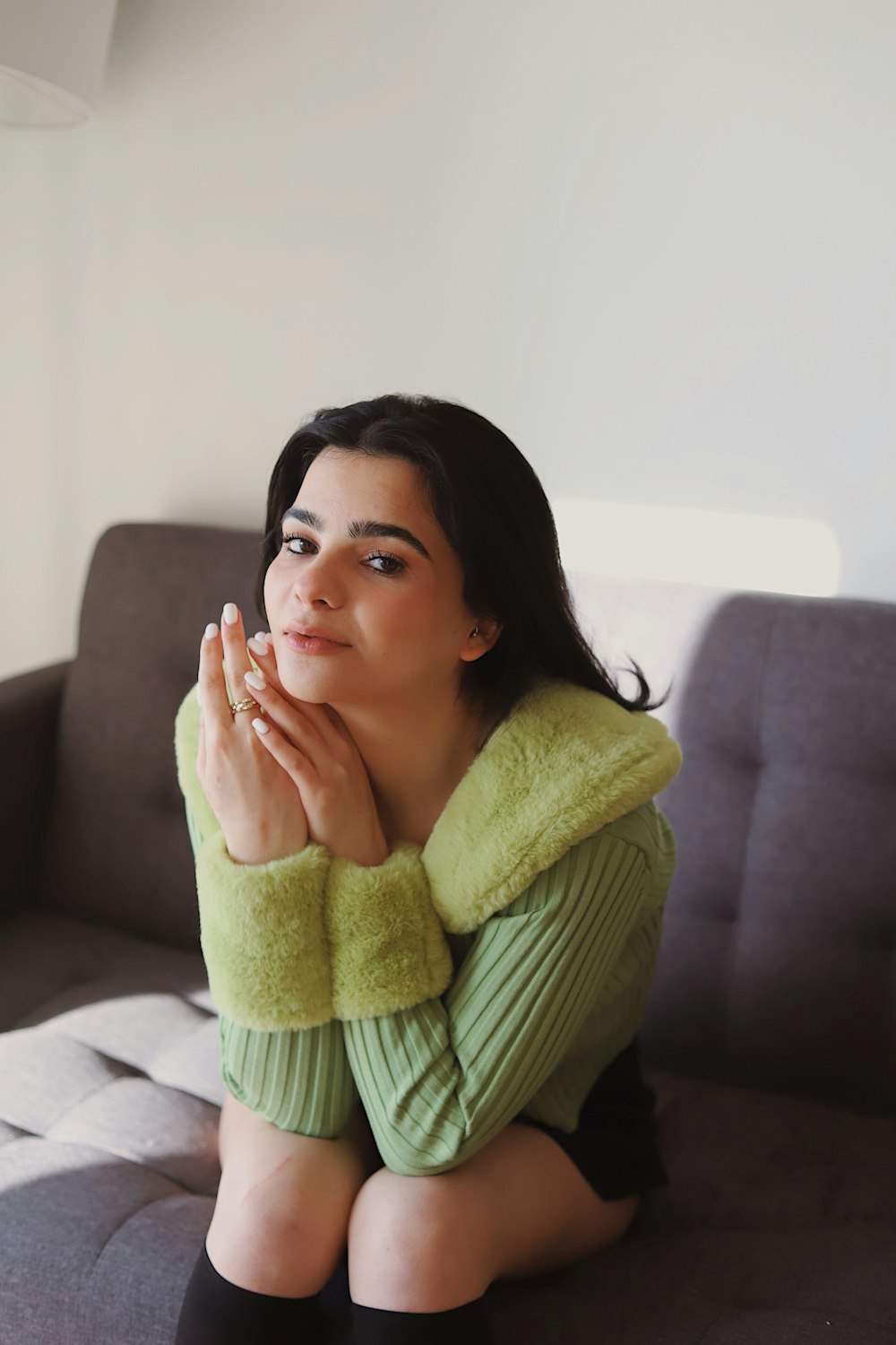 woman in green sweater sitting on white couch