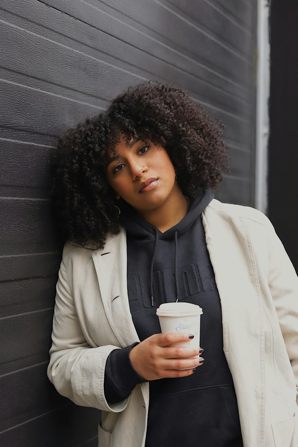 woman in white coat holding white disposable cup