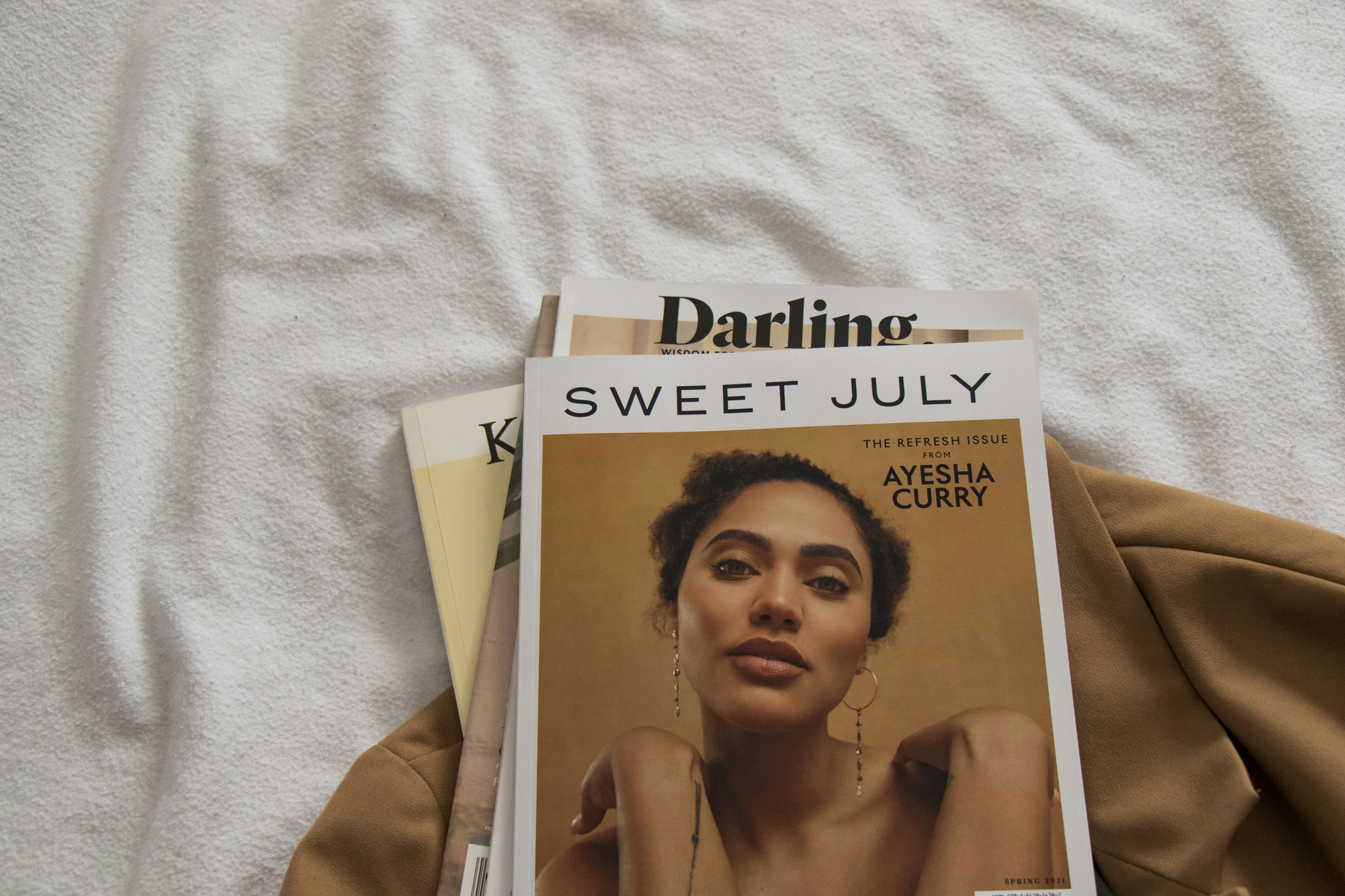 a magazine sitting on top of a bed next to a pair of scissors