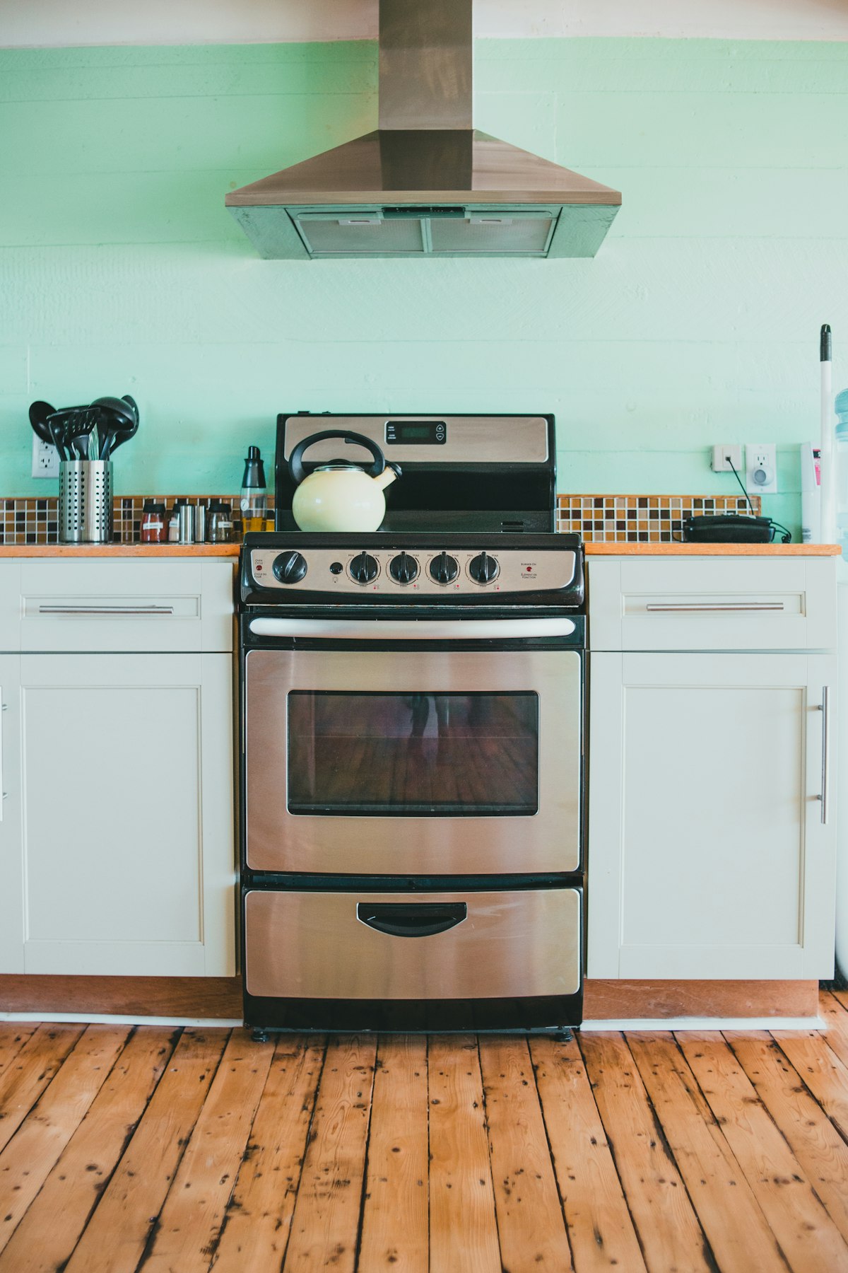 Cocina con horno de acero inoxidable empotrado entre muebles blancos, con la puerta del horno y la mesada a los lados