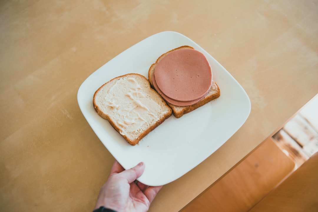 person holding white ceramic plate with brown pastry