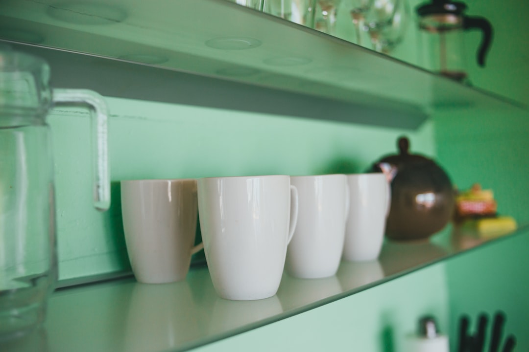 white ceramic mugs on white wooden shelf