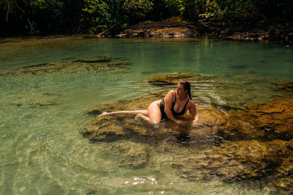 woman in black bikini lying on water during daytime