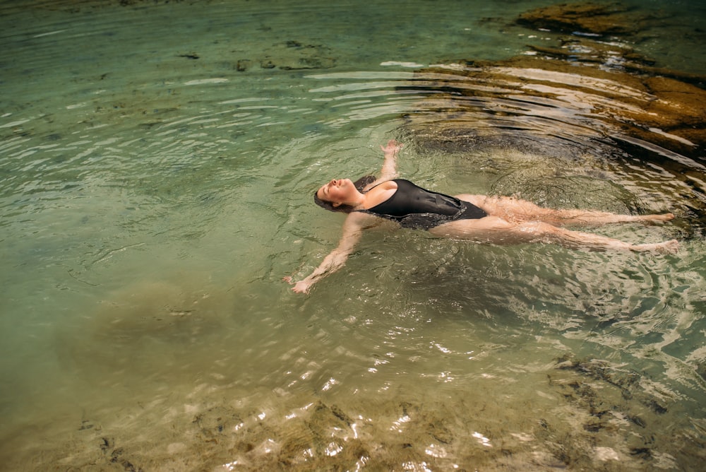 man in black shorts swimming on water during daytime