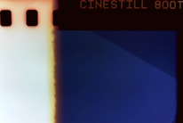 A photographic negative with text indicating 'CINESTILL 800T' at the top. The image has a prominent blue section on the right with a gradient transition to a lighter section on the left, marked by a vertical fading line. The border contains small rectangular perforations on the left side.