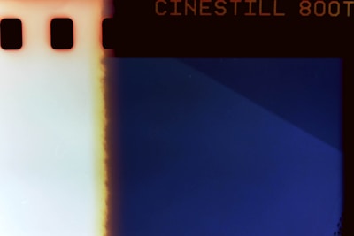 A photographic negative with text indicating 'CINESTILL 800T' at the top. The image has a prominent blue section on the right with a gradient transition to a lighter section on the left, marked by a vertical fading line. The border contains small rectangular perforations on the left side.