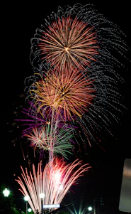 A vibrant fireworks factory workshop with skilled workers assembling colorful fireworks under bright lighting.