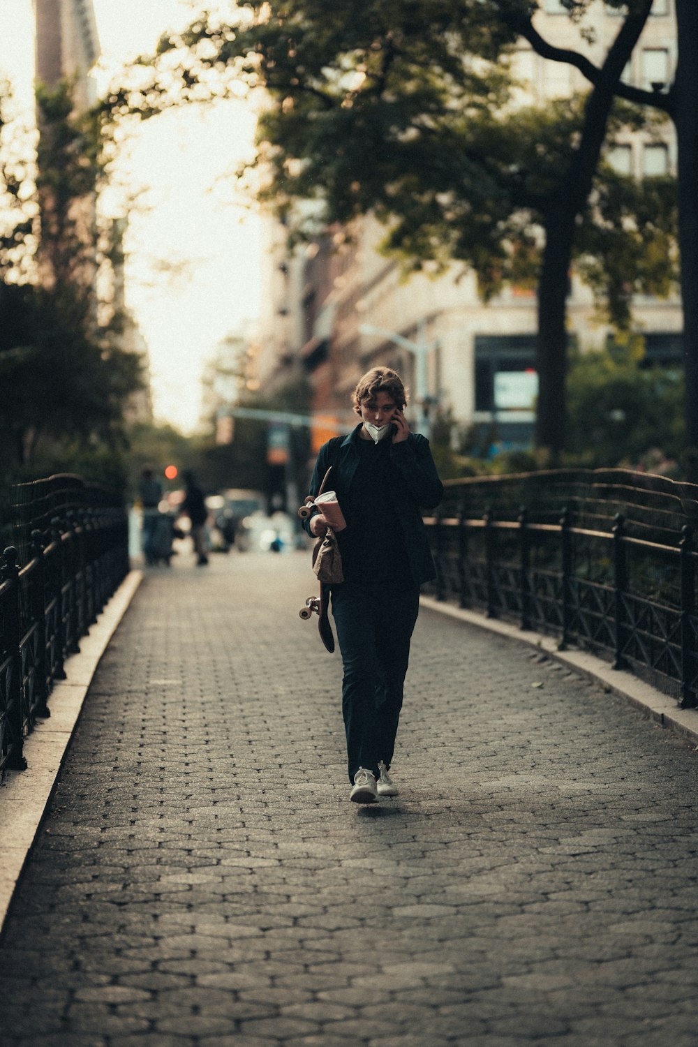 femme en manteau noir marchant sur le trottoir pendant la journée