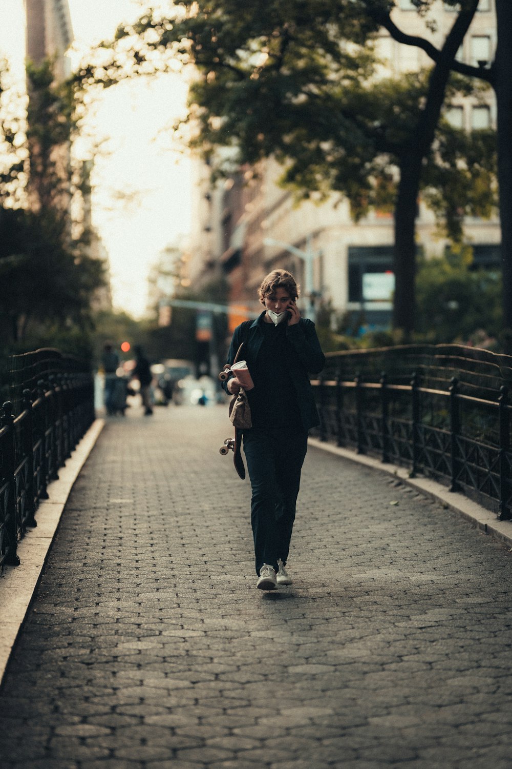 Mujer con abrigo negro caminando en la acera durante el día