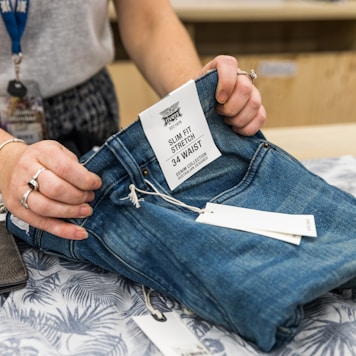 person in blue denim jeans holding white paper