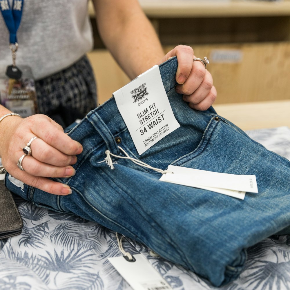 person in blue denim jeans holding white paper