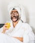 man in white bathrobe holding clear drinking glass with yellow liquid