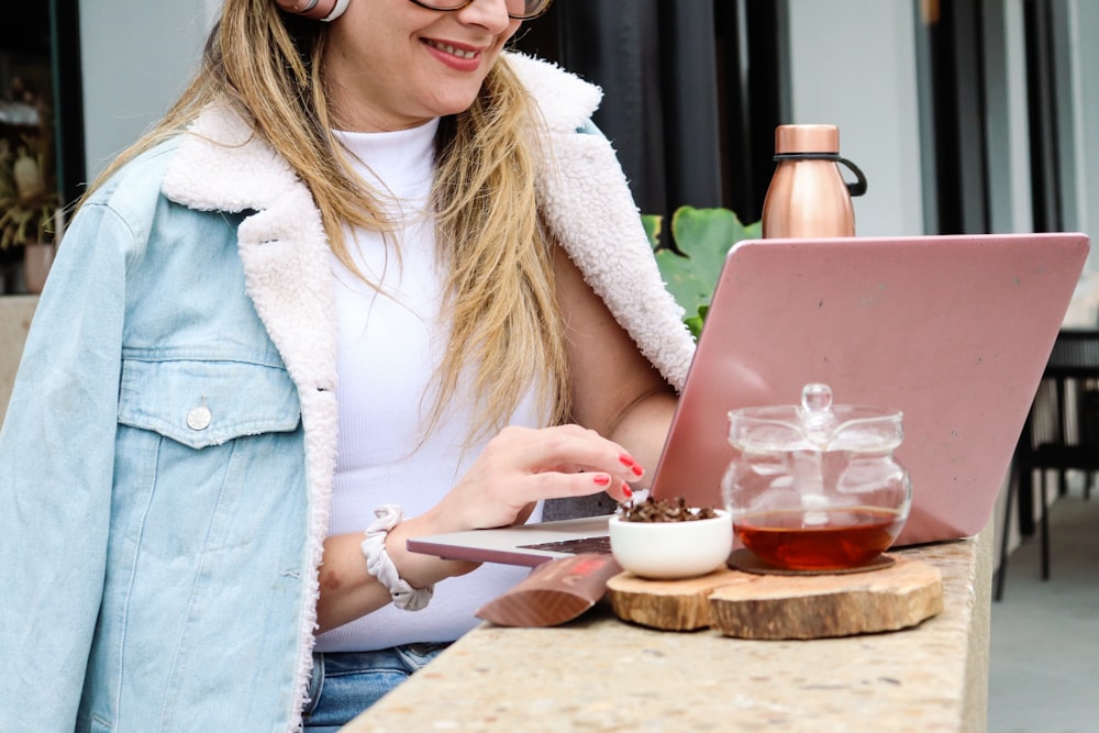 woman in white cardigan holding a silver fork and a glass of drink