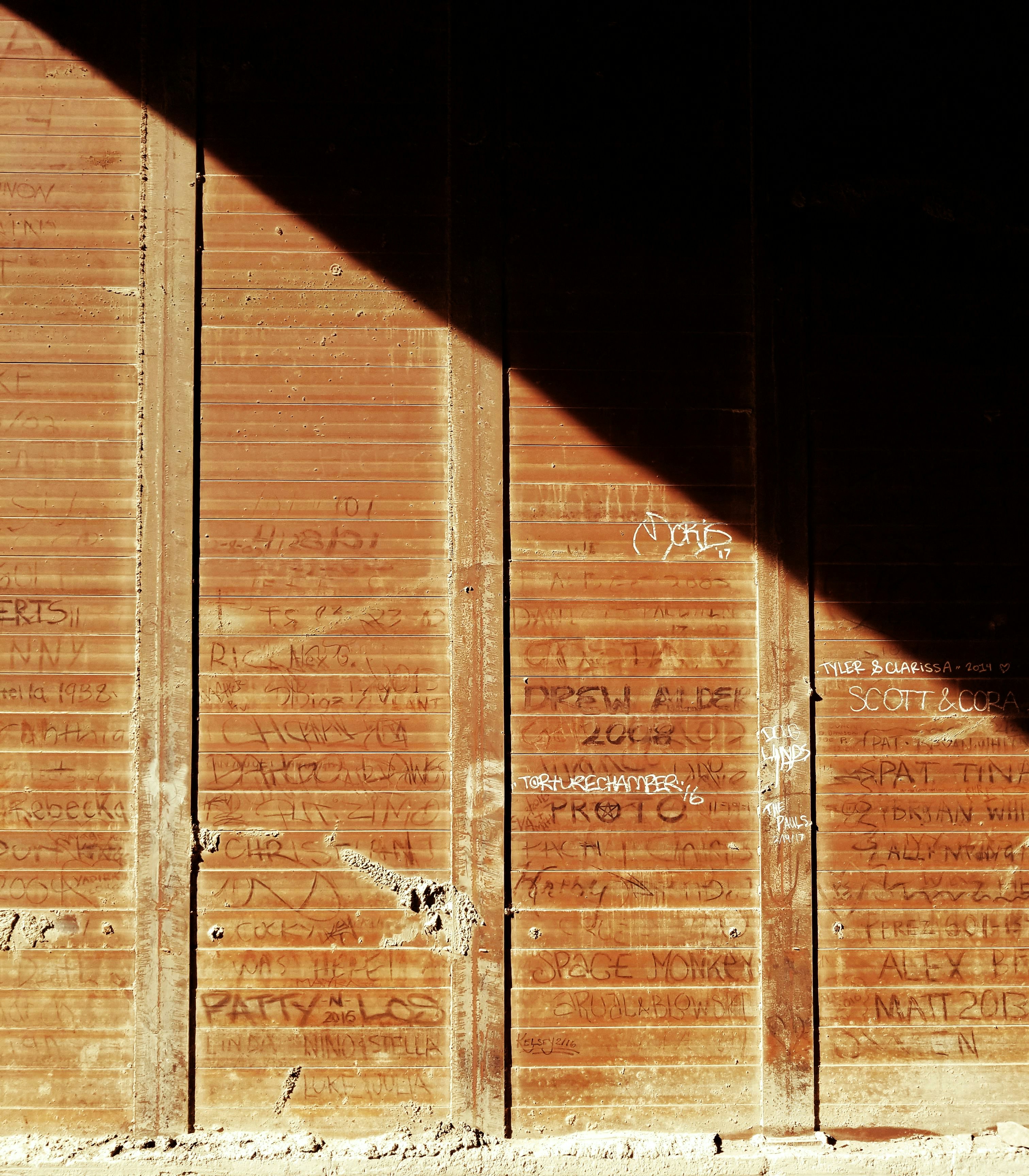 Un hombre montando una patineta por una calle debajo de un puente