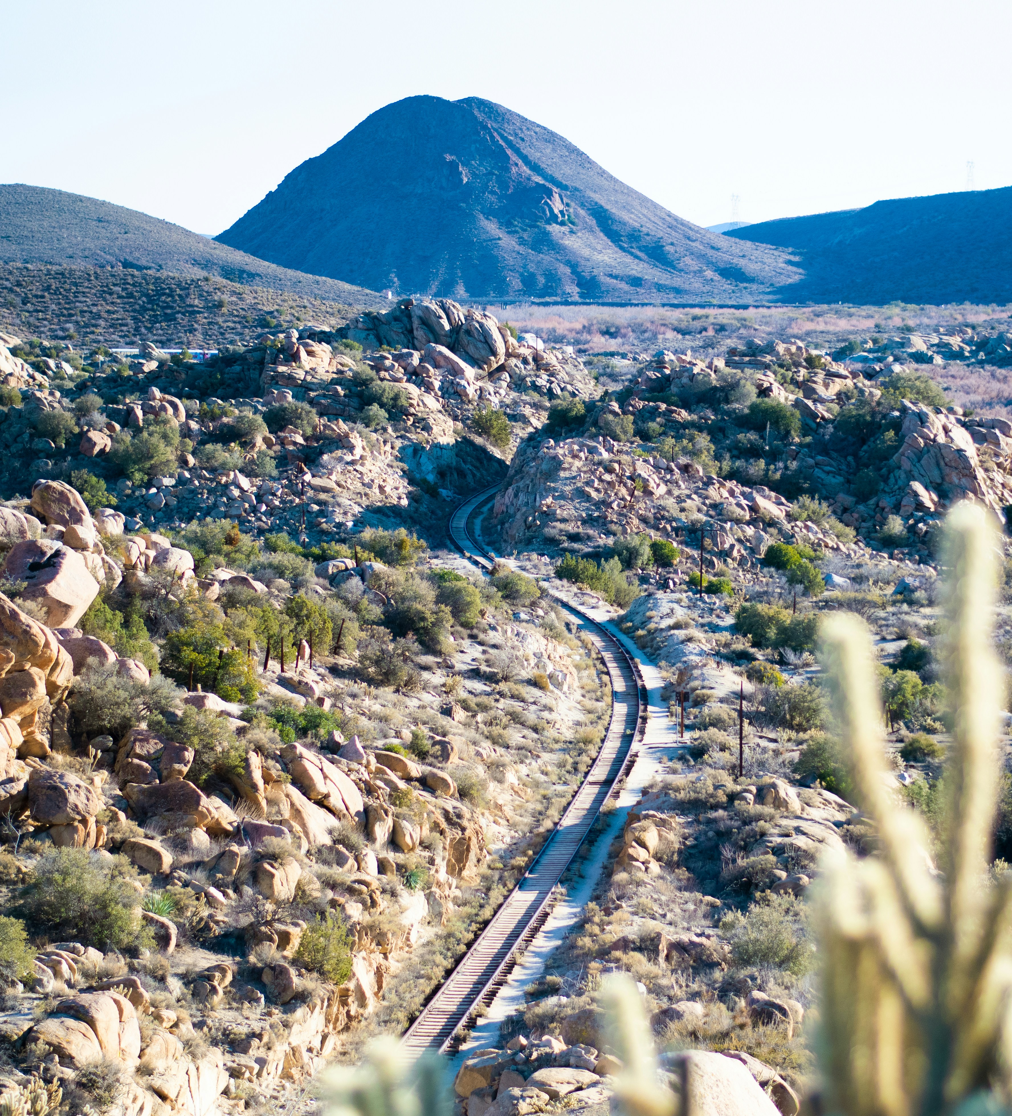 Un tren viajando por el desierto con una montaña al fondo