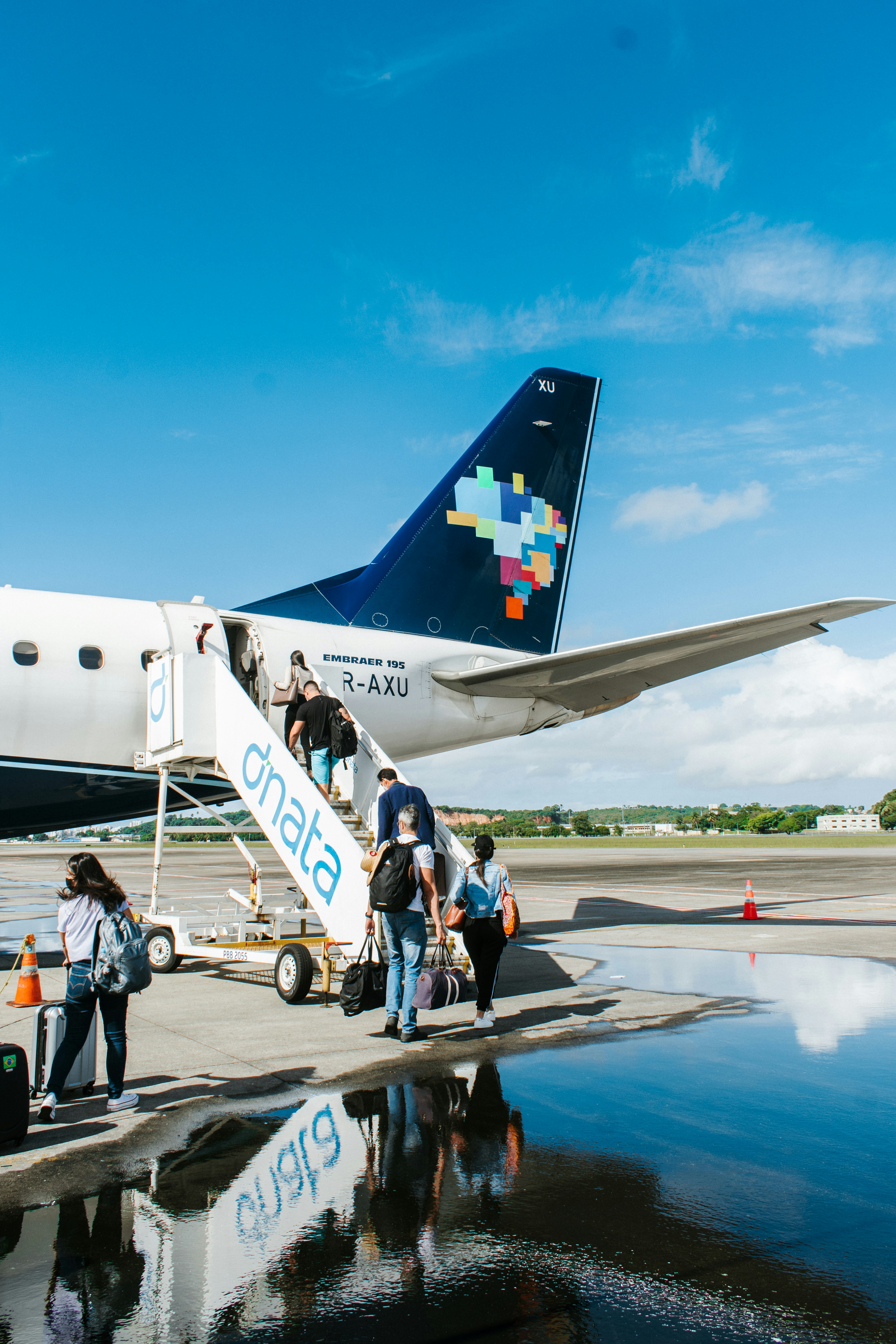 people walking near white and blue airplane under blue sky during daytime