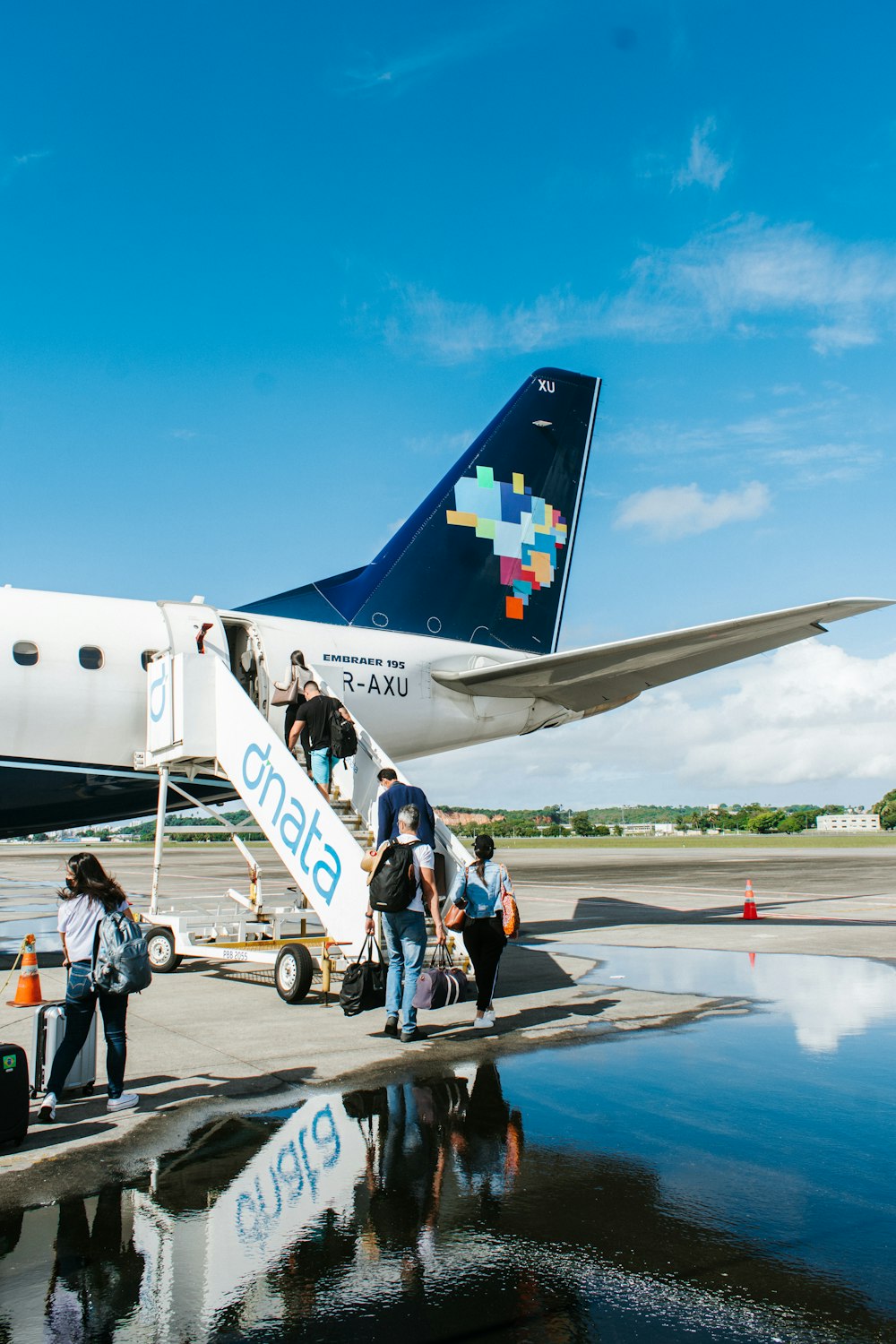 people walking near white and blue airplane under blue sky during daytime