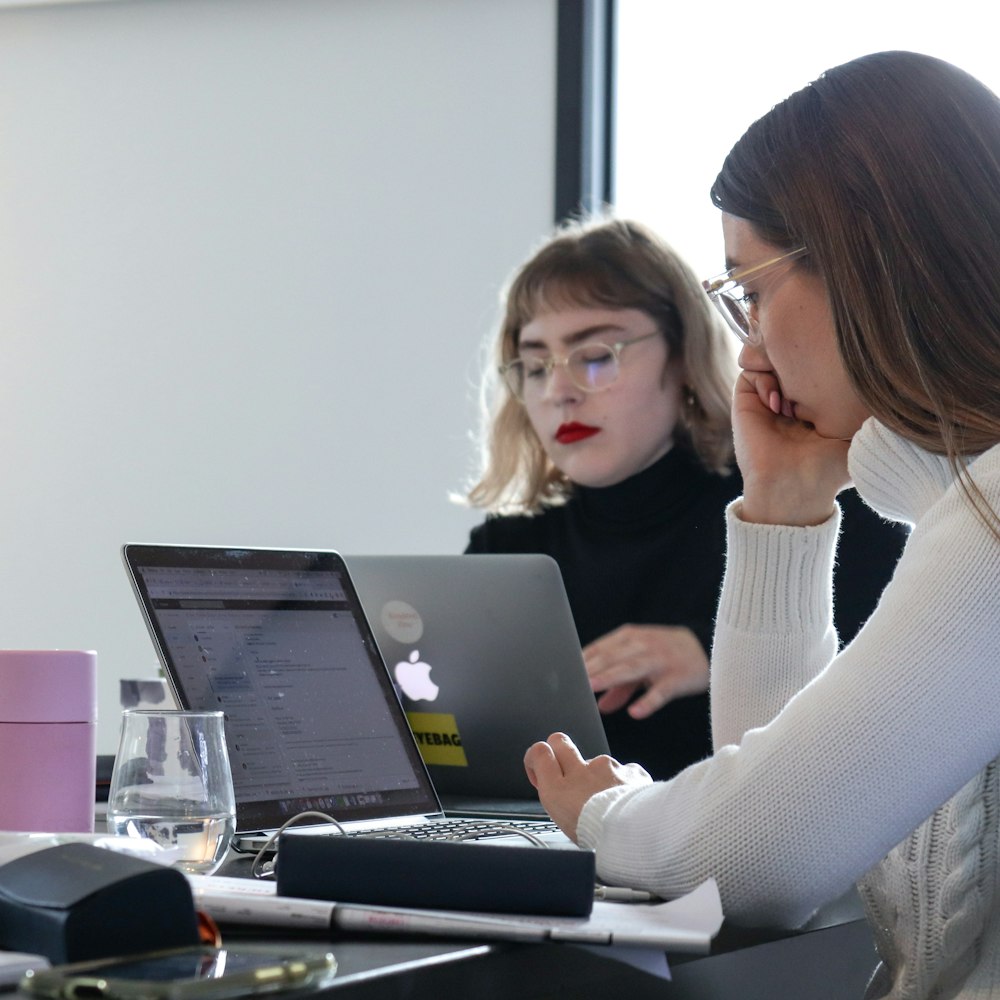 femme en pull blanc à l’aide d’un ordinateur portable