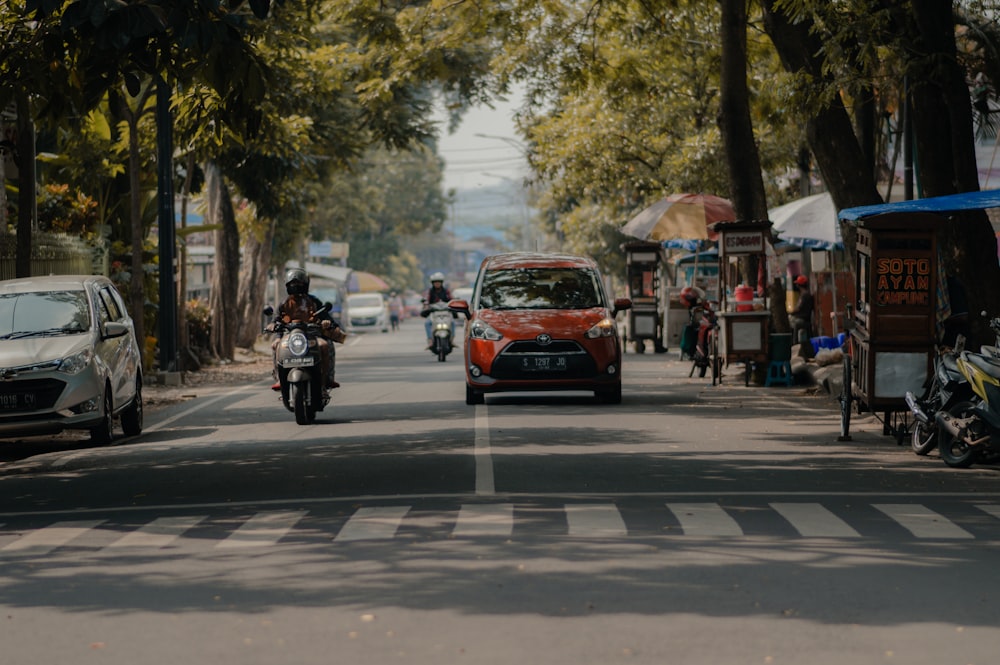 a car driving down a street next to a motorcycle