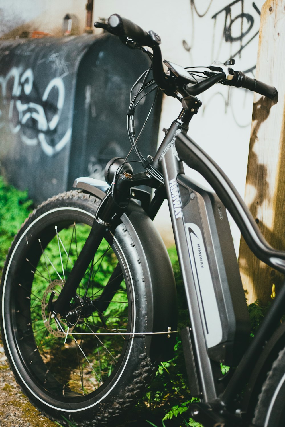 rueda de bicicleta negra apoyada en la valla de madera negra