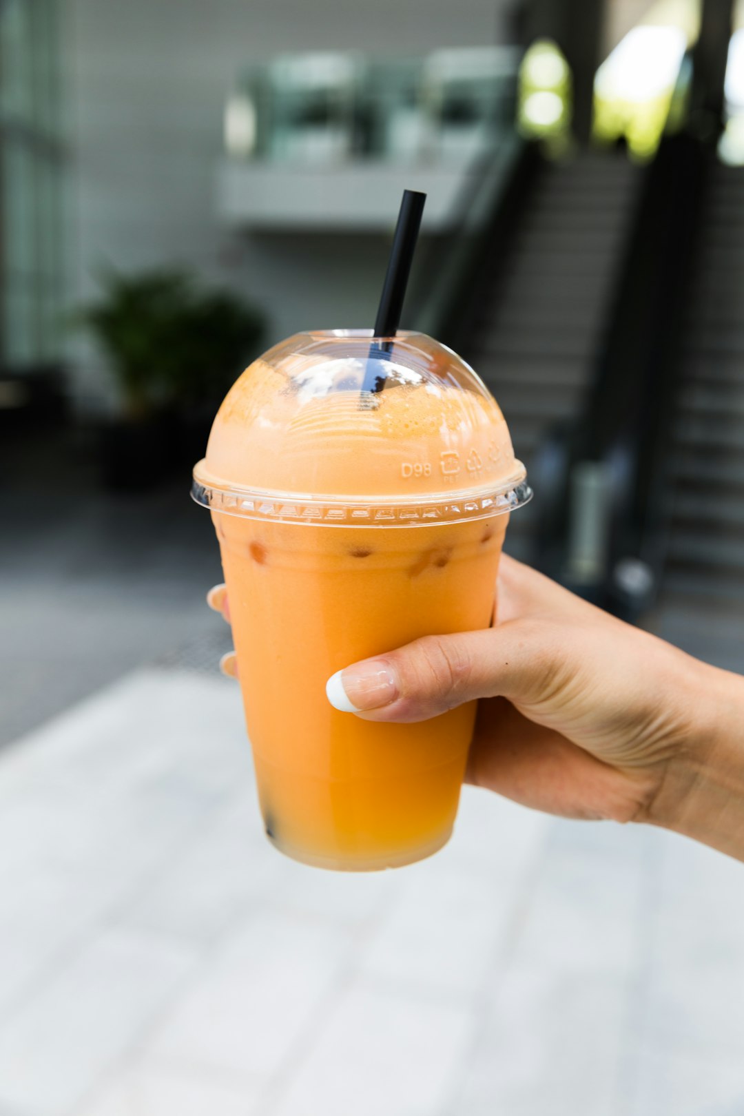 person holding orange juice in clear plastic cup