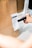 A hand is holding a scanner over a delivery receipt attached to a brown paper bag. The setting appears to be a workspace or a kitchen counter.