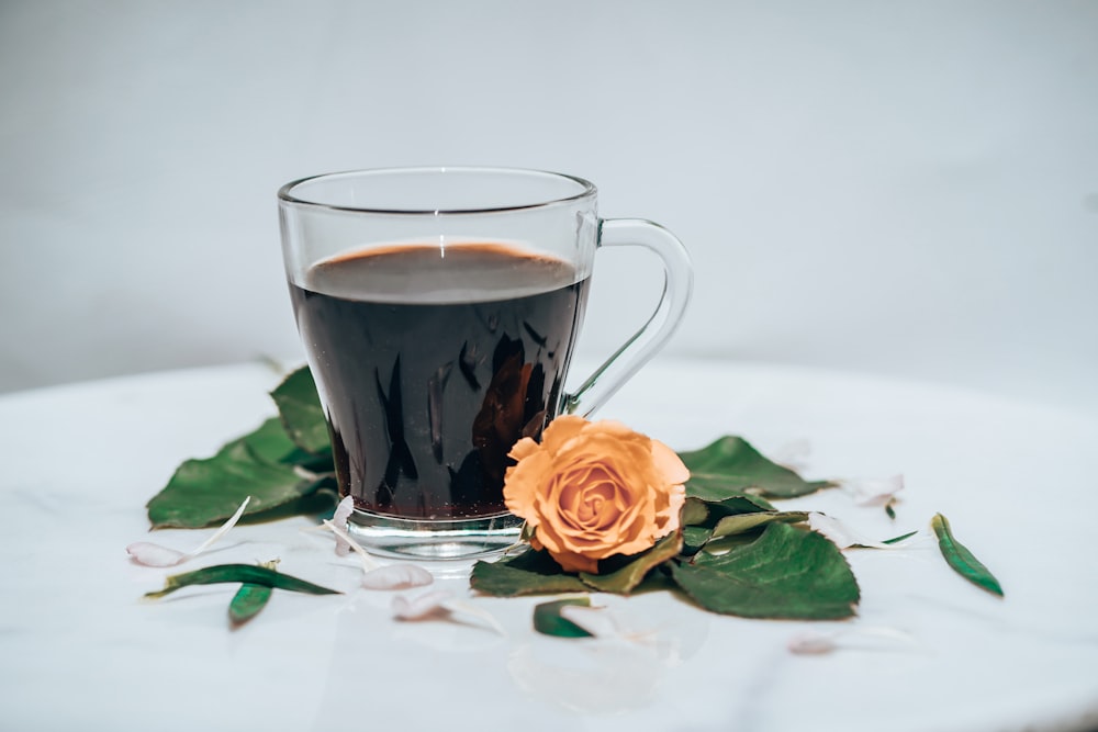 clear glass mug with brown liquid on white table