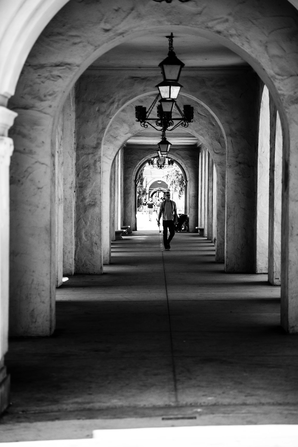 a black and white photo of a person walking down a walkway
