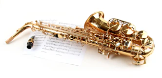 a golden saxophone sitting on top of a sheet of music