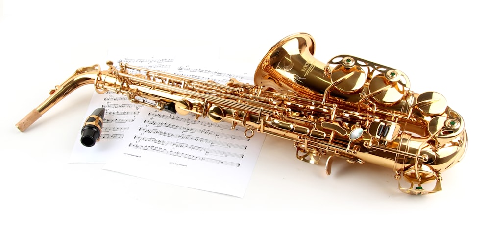 a golden saxophone sitting on top of a sheet of music