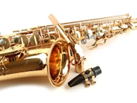 Side view of a saxophone mouthpiece with delicate cream and silver mandalas blurred in the background.