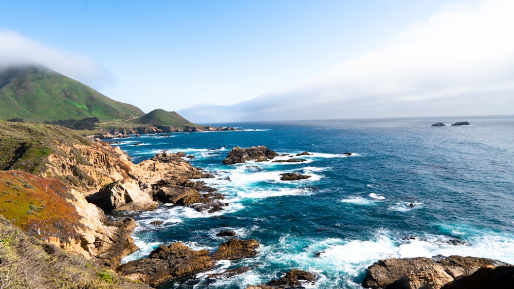 a scenic view of the ocean with a mountain in the background